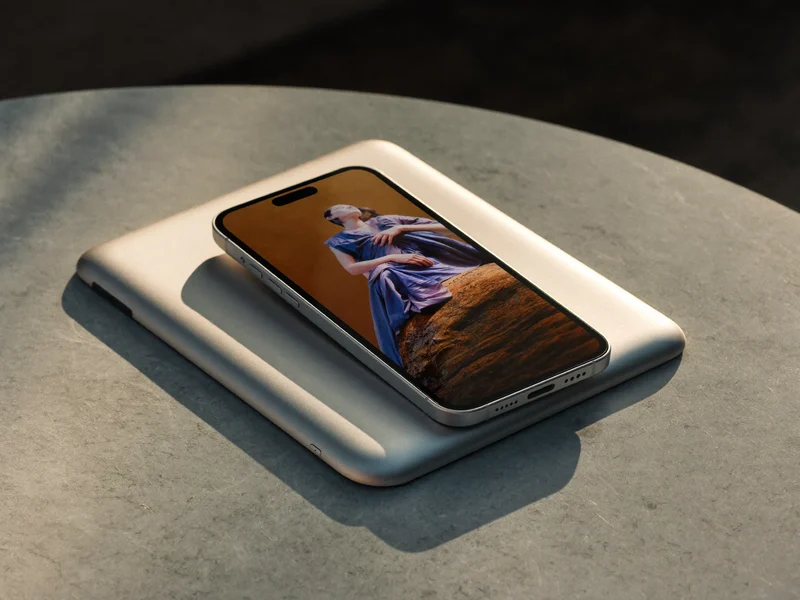 Slank smartphone ved siden af en kompakt tablet på lys stenoverflade